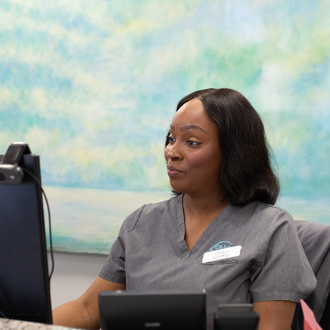 A woman sitting at a front desk on a computer