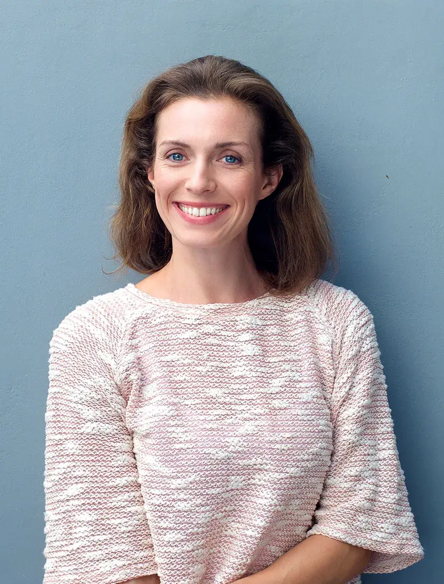 Cataracts Service Intro Woman smiling while standing in front of blue wall